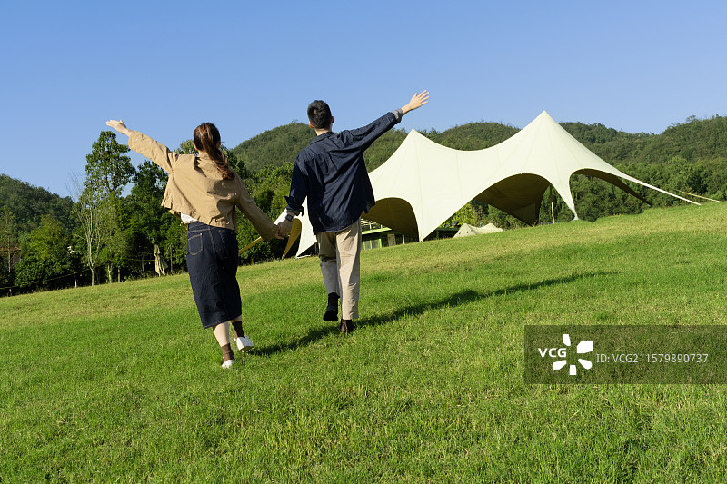 手牵手在露营地散步的年轻情侣图片素材