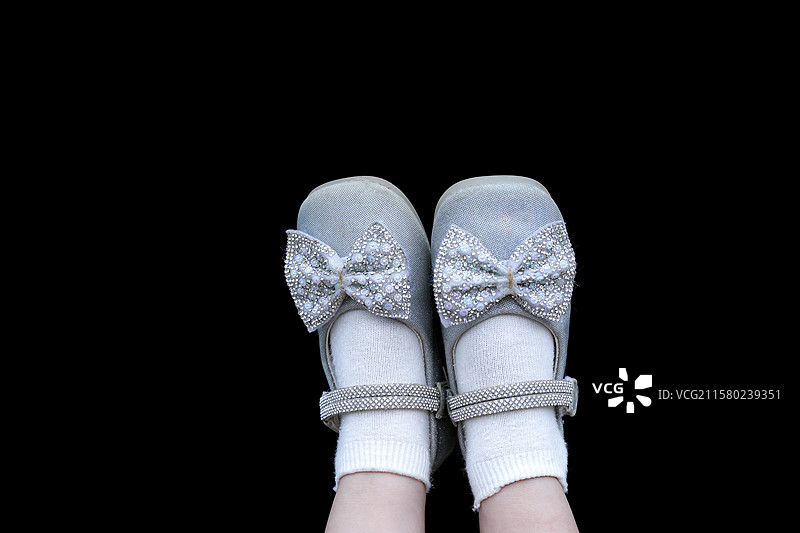 黑色背景上穿着闪闪发光水晶鞋的儿童脚的背景图图片素材