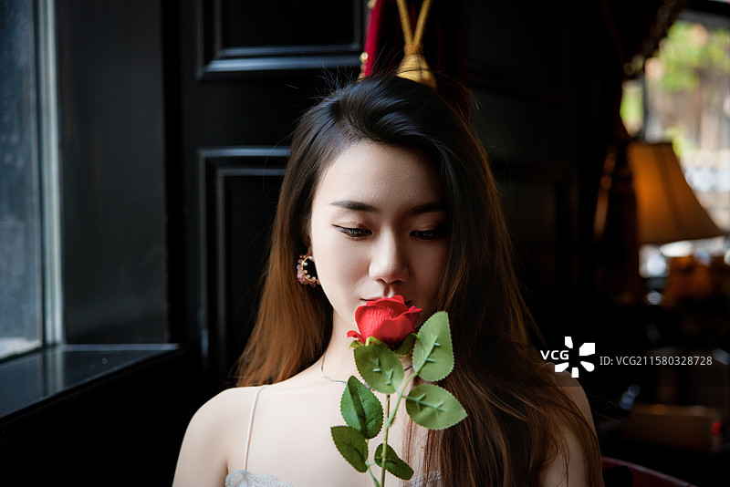 坐在餐厅里捧着玫瑰的年轻女子图片素材