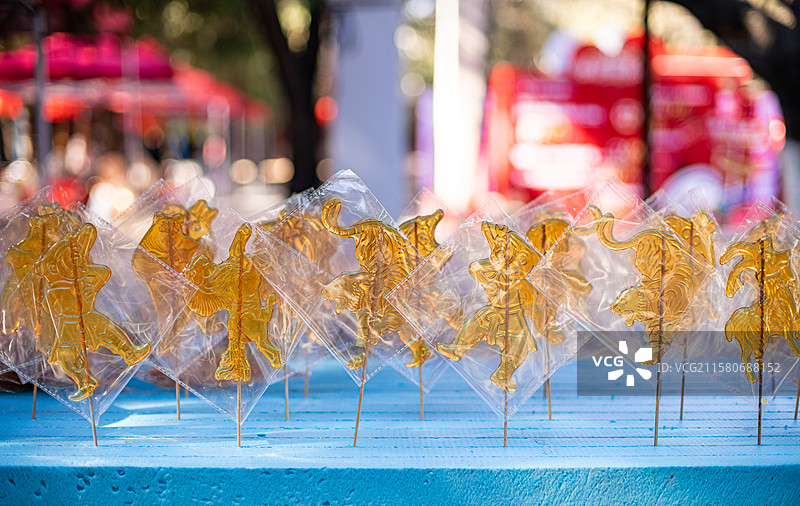 中国传统文化手艺拍摄主题，一排包装好的老虎山羊奥特曼熊二小猪佩奇孙悟空糖画，户外无人白昼图像摄影图片素材