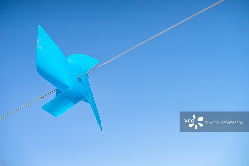 中国休闲娱乐设备用品拍摄主题，线绳上拴着一个彩色的纸质风车，户外白昼无人图像摄影图片素材