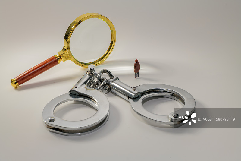 白色背景下放大镜手铐和模型小人的高角度视图图片素材