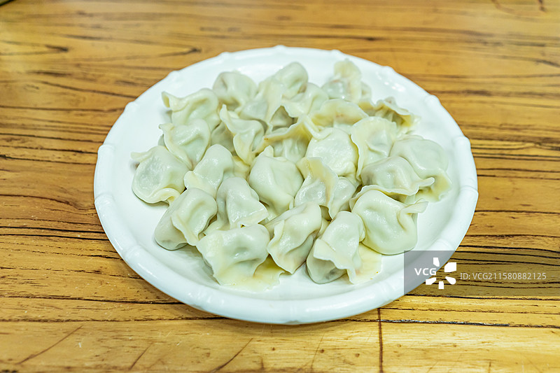 中国传统节日过年吃饺子拍摄主题，盘子盛着一碗热腾腾的水饺，室内无人图像摄影图片素材