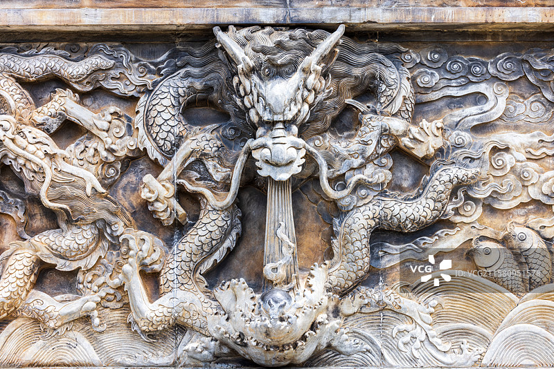 传统建筑上的精美龙形浮雕，细节丰富，象征着力量和吉祥，在深色石材的衬托下显得格外生动和富有艺术魅力图片素材