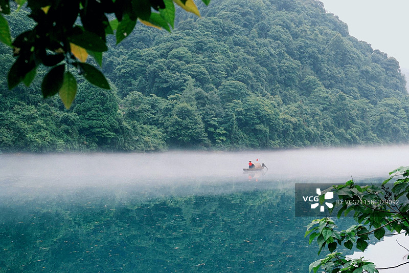 湖面如镜，倒映出沿岸的景色，湖面雾气缭绕，驾一叶扁舟，如入人间仙境图片素材