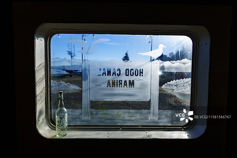 胡德运河，美国，胡德运河码头，窗户上的刻字标志，以及一瓶空啤酒。图片素材