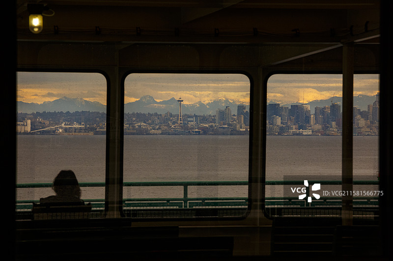 美国西雅图，巴恩布里奇岛渡轮上俯瞰黄昏时分的西雅图天际线，渡轮上的侧面人影。图片素材