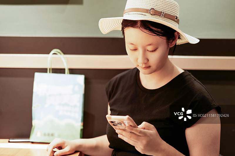 戴帽子的女子在室内使用手机图片素材