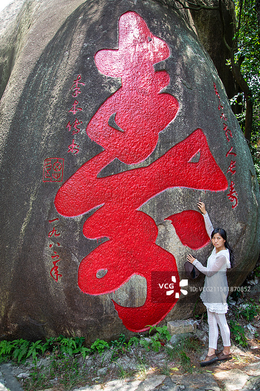 女子在刻有红色寿字的巨石旁留影图片素材