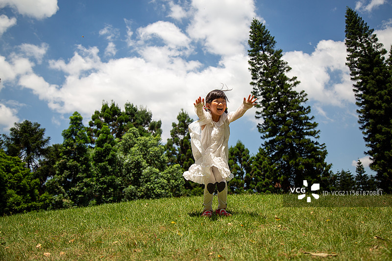 小女孩在草地上跳跃图片素材