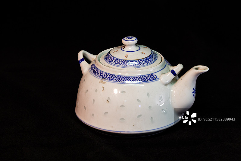 黑色背景下茶壶的特写镜头，黑色背景下茶壶的高角度视图，传统餐具景德镇青花玲珑瓷茶壶图片素材