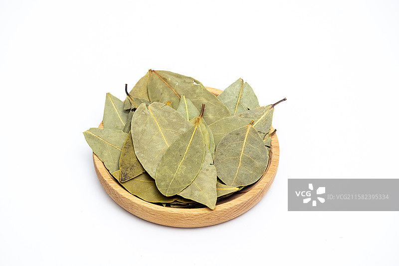 白色背景中木盘子里装着晾晒干的香叶叶子调料图片素材