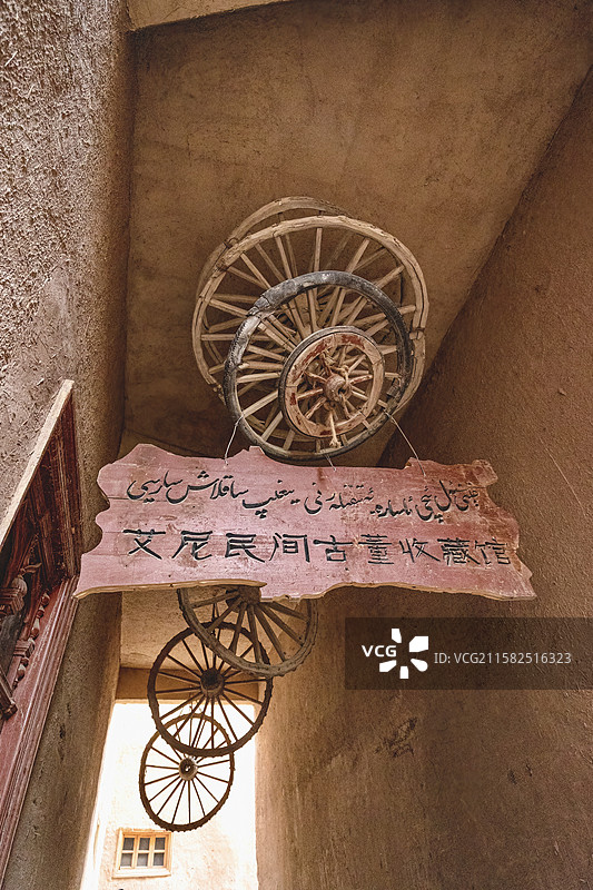 新疆维吾尔族喀什高台民居景点艾尼民间古董收藏馆土墙街道，装饰有马车车轮轮毂图片素材