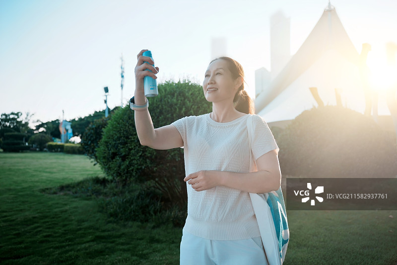 户外喷防晒霜的中年女性图片素材