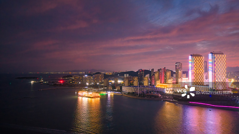 夏天傍晚蓝调时刻漫天火烧云晚霞下的青岛市黄岛区海岸线城市夜景图片素材