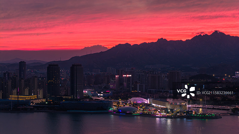 夏天傍晚蓝调时刻漫天火烧云晚霞下的青岛市黄岛区海岸线城市夜景图片素材