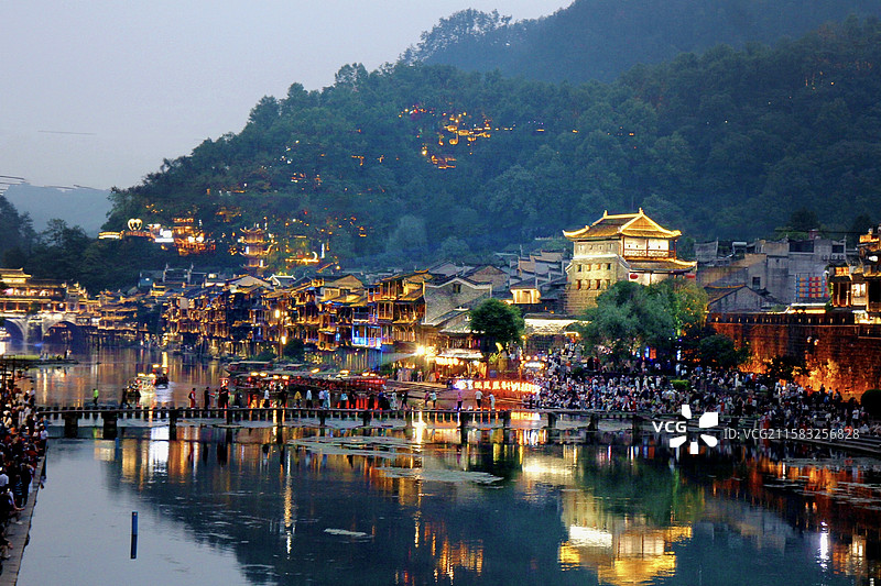 凤凰古城的夜幕降临，沱江两岸的灯火悄然亮起，与古朴的建筑交相辉映，构成了一幅如梦似幻的画卷。图片素材