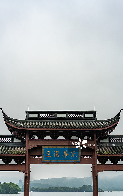 雨中的杭州西湖光华复旦牌坊建筑与雾色背景里的远山雷峰塔建筑湖面游船景观图片素材