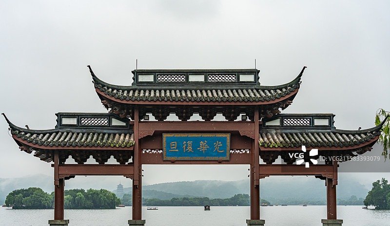 雨中的杭州西湖光华复旦牌坊建筑与雾色背景里的远山雷峰塔建筑湖面游船景观图片素材