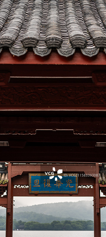 雨中的杭州西湖光华复旦牌坊建筑与雾色背景里的远山雷峰塔建筑湖面游船景观图片素材