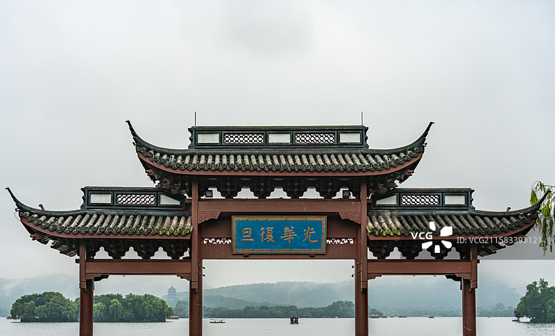 雨中的杭州西湖光华复旦牌坊建筑与雾色背景里的远山雷峰塔建筑湖面游船景观图片素材