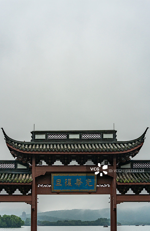 雨中的杭州西湖光华复旦牌坊建筑与雾色背景里的远山雷峰塔建筑湖面游船景观图片素材