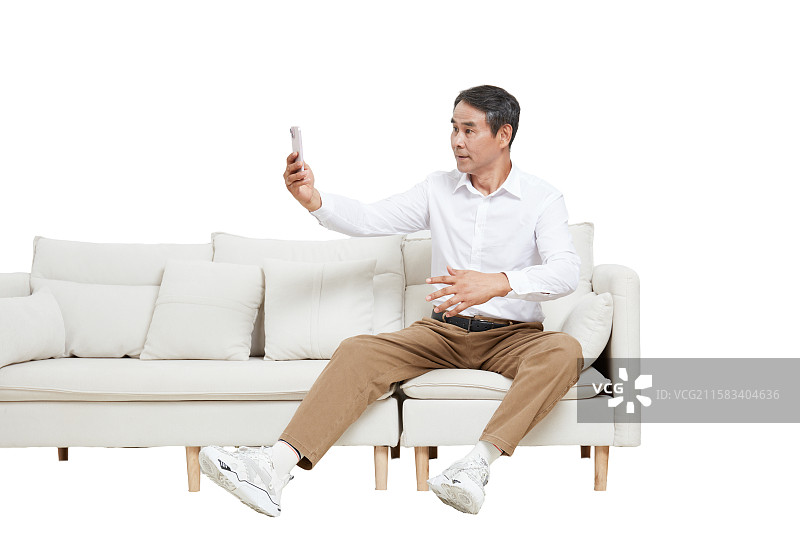 坐在沙发上的一个中老年男性拿手机自拍图片素材