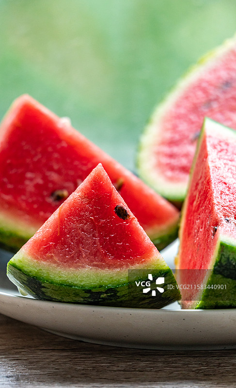 夏天必备水果西瓜小糖丸西瓜.绿色虚化背景中的西瓜切块的西瓜西瓜瓤特写镜头图片素材