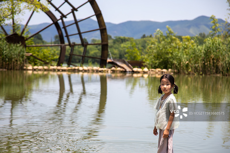 水边的女孩与古老水车图片素材