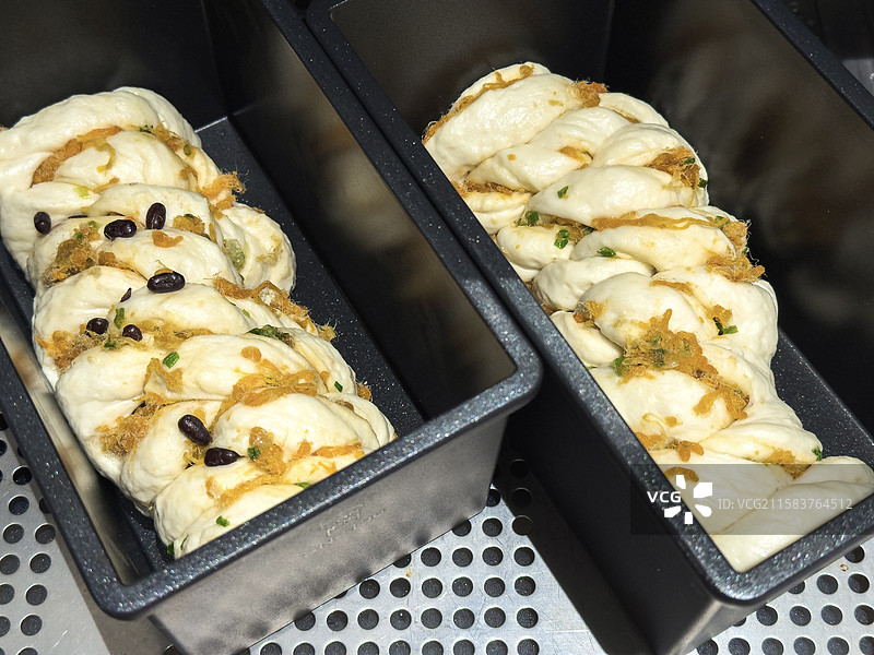 装在黑色烘焙盒里待进入烤箱的香葱肉松面包图片素材