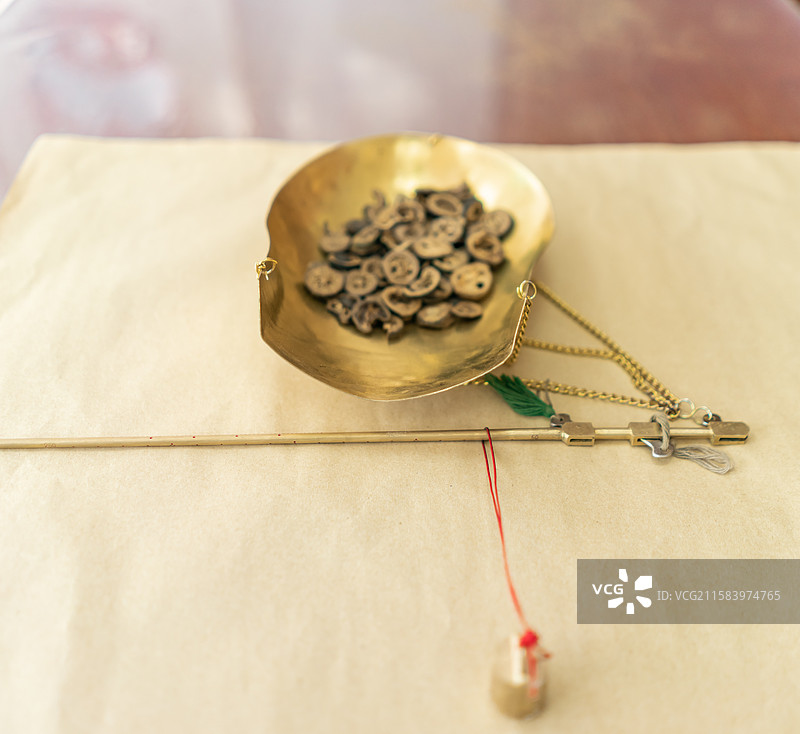 中国中医药服务拍摄主题，中医医院，黄色纸上放着一杆黄色铜制秤和一堆中草药，室内无人图像摄影图片素材