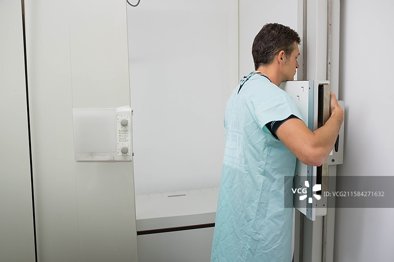 放射科技师在放射科室的成像桌上调整数字X光探测器图片素材