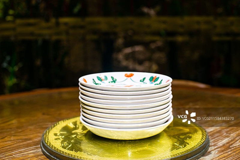 中国餐饮餐厅饭店饭馆行业，空的餐桌拍摄主题，中国传统木制圆桌上的叠起来的盘子餐具，室内无人图像摄影图片素材