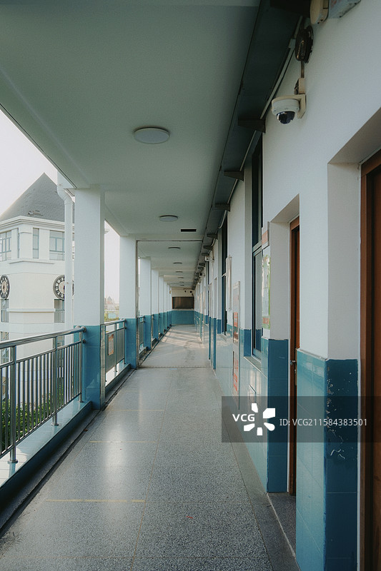 校园教学楼走廊，蓝白相间墙体；两侧教室木门。图片素材