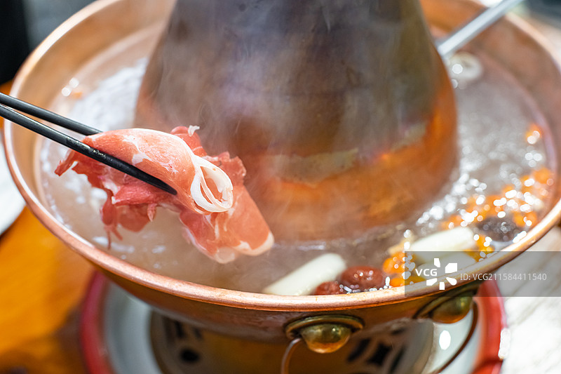 中国饮食产业拍摄主题，沸腾的老北京铜锅锅火锅，筷子夹起不锈钢盘子里的羊肉卷，室内无人图像摄影图片素材