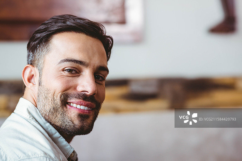 穿着浅色衬衫的男子在木质装饰的休息室中回头，留有空白空间图片素材