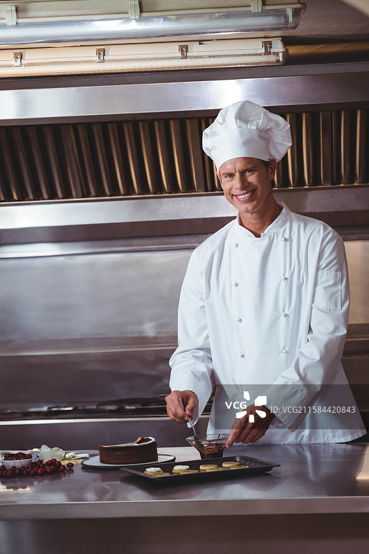 融化的巧克力从勺子流向商业厨房不锈钢台面上的糕点图片素材