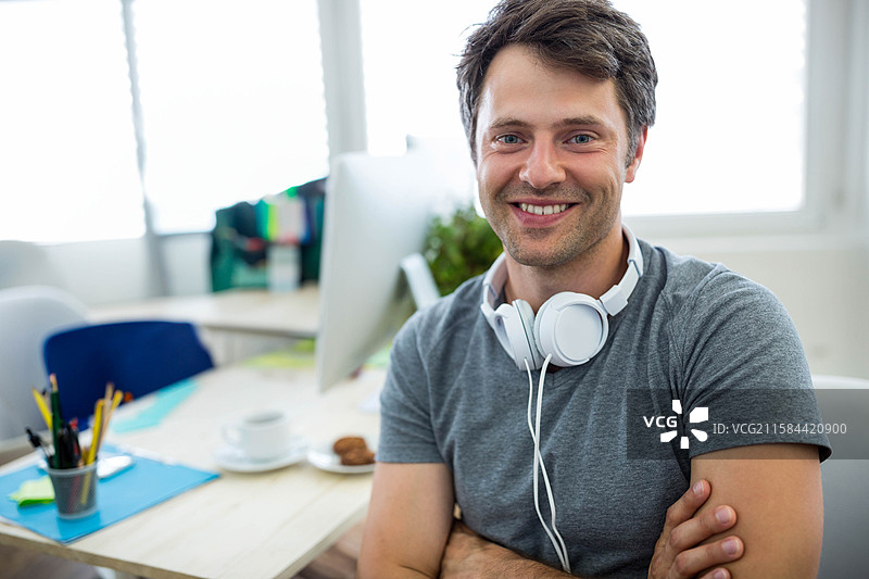 电脑显示器发光，耳机放在桌子上，旁边有咖啡杯和饼干，留白空间图片素材