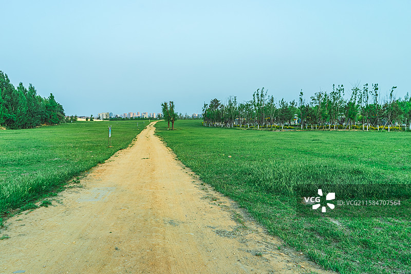 中国非都市风光拍摄主题，绿色的草坪，蓝色的天空和黄色的土路主干道，户外白昼无人图像摄影图片素材