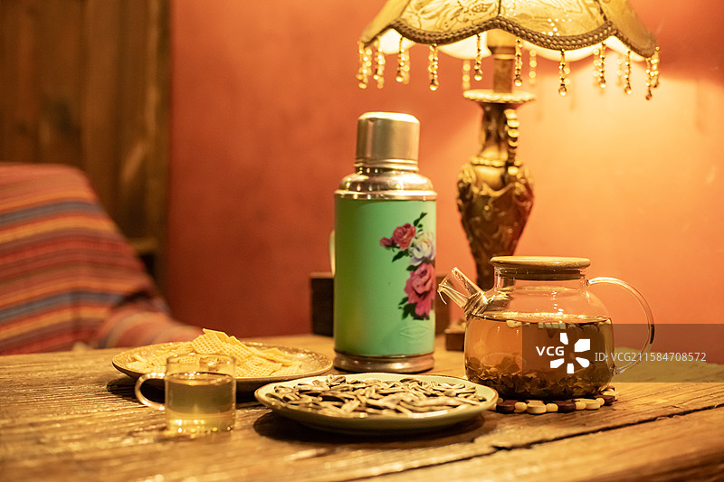 中国休闲娱乐健康生活方式拍摄主题，木制桌子上一堆黄色的锅巴瓜子小吃暖水壶和玻璃杯，室内无人图像摄影图片素材