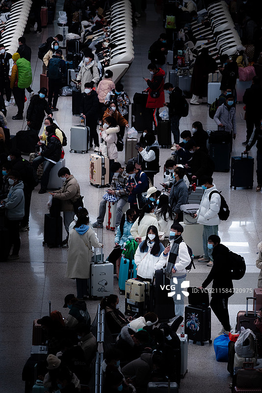 新冠疫情期间在南昌高铁站戴着口罩的人群中间，一对情侣正在候车图片素材
