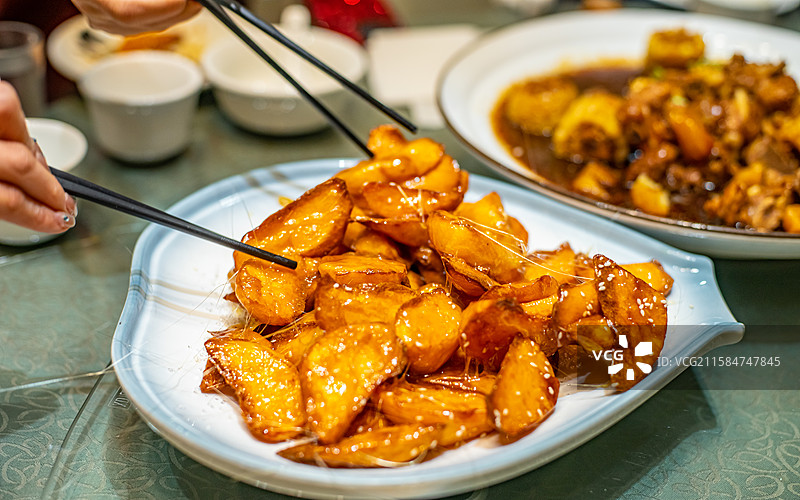 中国餐饮行业饮食产业，传统经典中国食品，一盘子正在拉丝的拔丝地瓜拔丝山药，室内无人图像图片素材