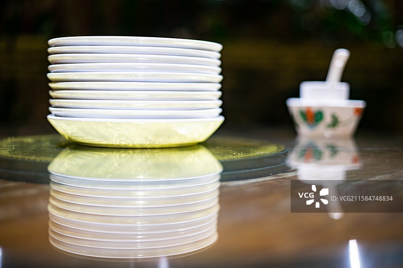 中国餐饮餐厅饭店饭馆行业，空的餐桌拍摄主题，中国传统木制圆桌上的叠起来的餐具，室内无人图像摄影图片素材