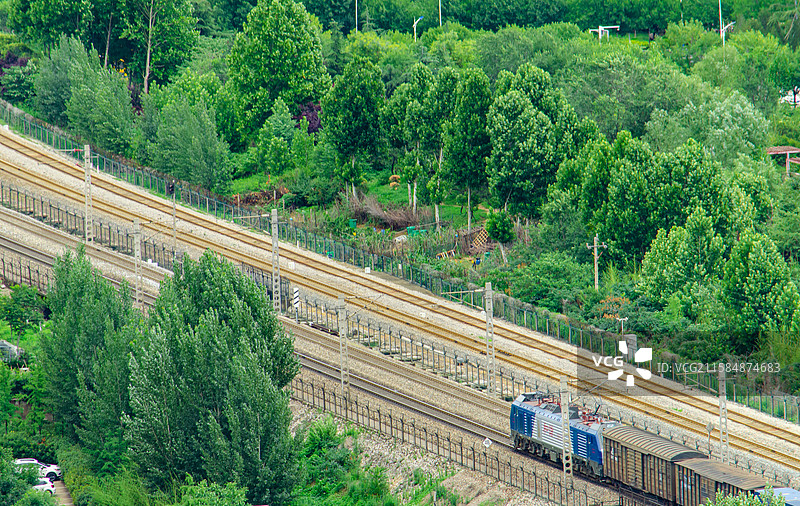 中国城市市风光拍摄主题，航拍视角俯拍铁路道轨和绿皮火车道和城市居住区，户外白昼无人图像摄影图片素材