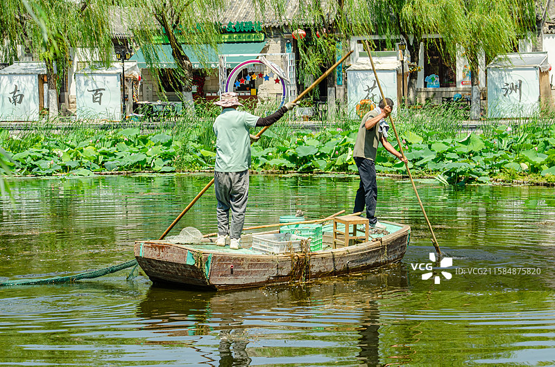 中国非都市风光拍摄主题，山东济南曲水亭街护城河湖泊河流清洁工在一艘小船上清理垃圾，户外白昼人图像摄影图片素材
