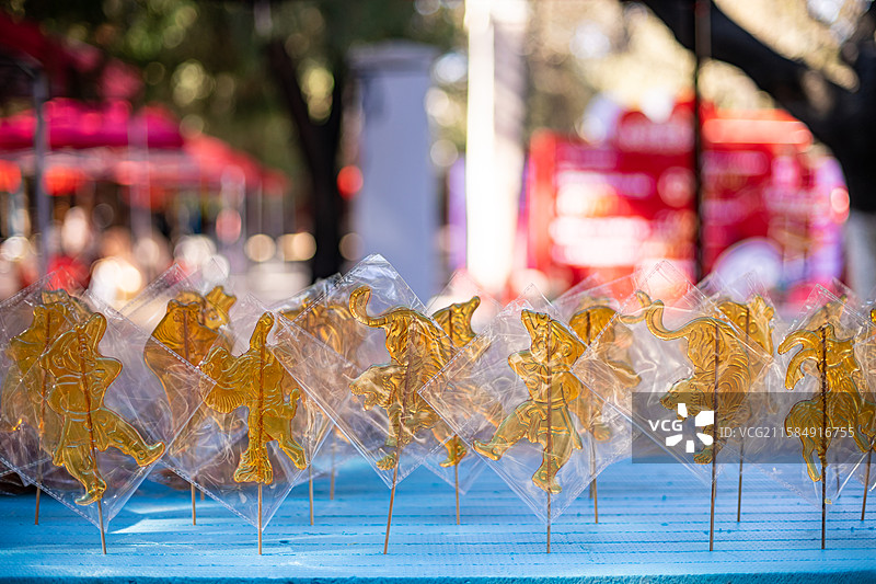 中国传统文化手艺拍摄主题，一排包装好的老虎山羊奥特曼熊二小猪佩奇孙悟空糖画，户外无人白昼图像摄影图片素材