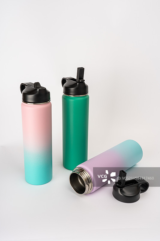 白色背景下的彩色不锈钢运动保温水杯图片素材