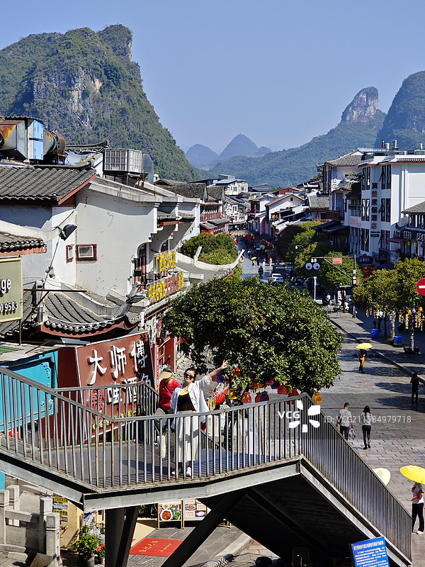 女游客在桂林阳朔西街过街桥上拍照打卡图片素材