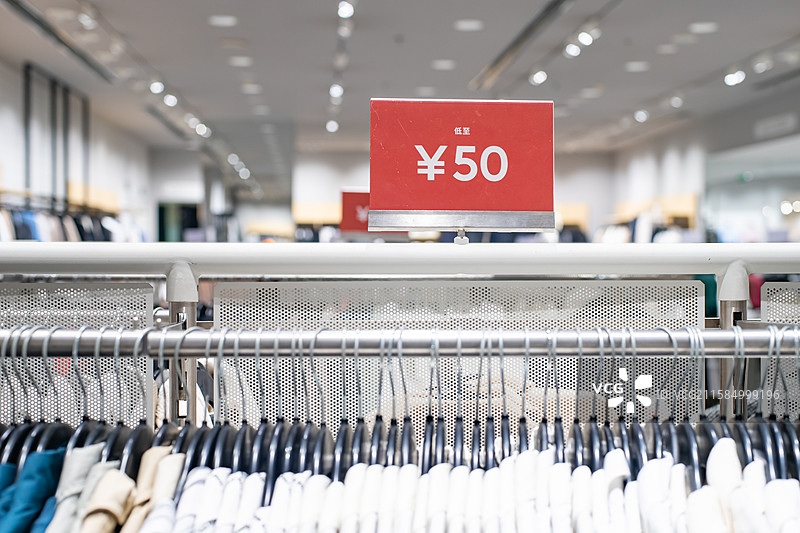 中国商场服装店的生活用品拍摄主题，货架上摆放着悬挂的整齐的衣服和打折价签，室内无人图像摄影图片素材
