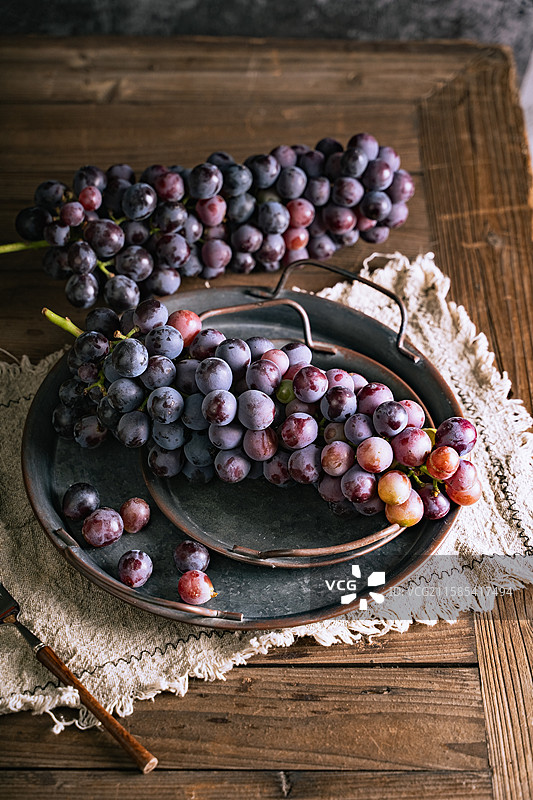 暗调静物美食摄影高视角盘子里成串的水果葡萄特写，展示了自然之物的美好，可用于健康生活方式的宣传图片素材